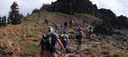 Group of people hiking up a grassy and rocky mountain side