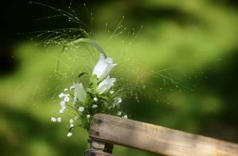 Close up view of a small bouquet of white flowers and baby's breath tied to a wooden chair